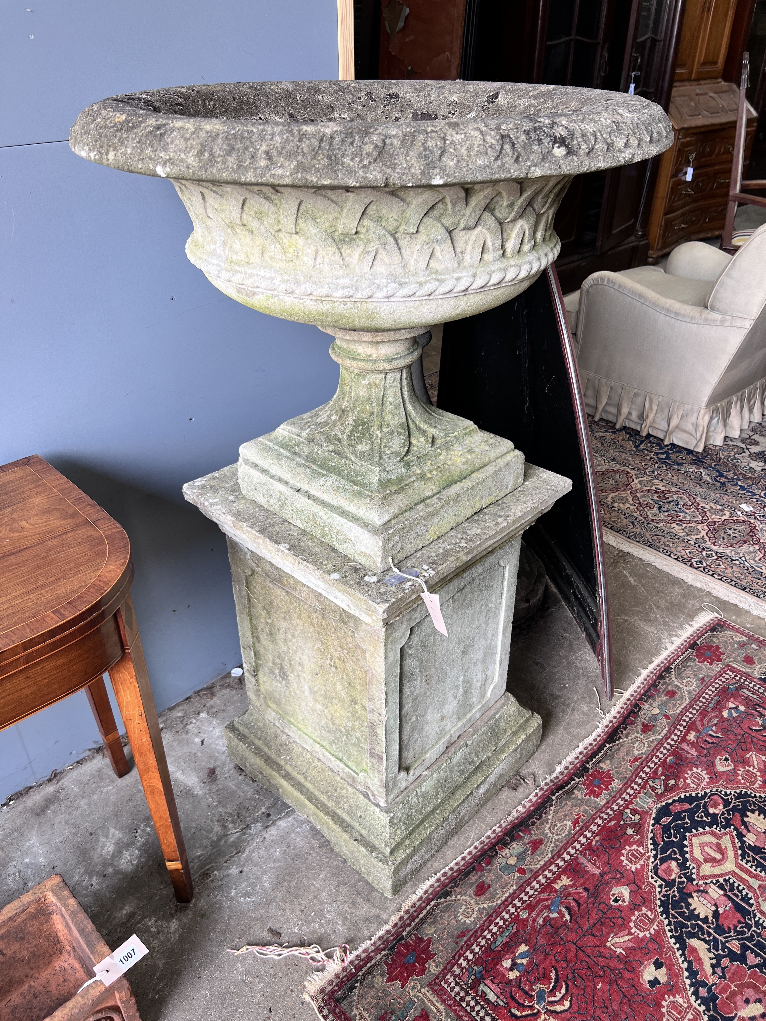 A circular reconstituted stone garden planter on square plinth, diameter 76cm, height 127cm